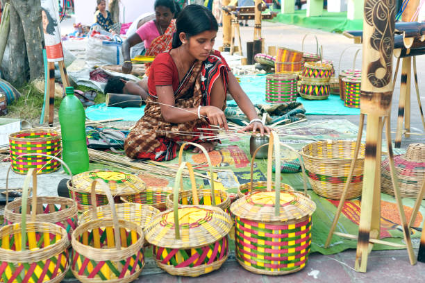 Kolkata, 03/01/2020: A lady artisan from rural community making bamboo / cane made handicrafts at Saras Mela, a handicraft fair organised annually to showcase West Bengal's handicraft. Several finished products are on retail display for sale.